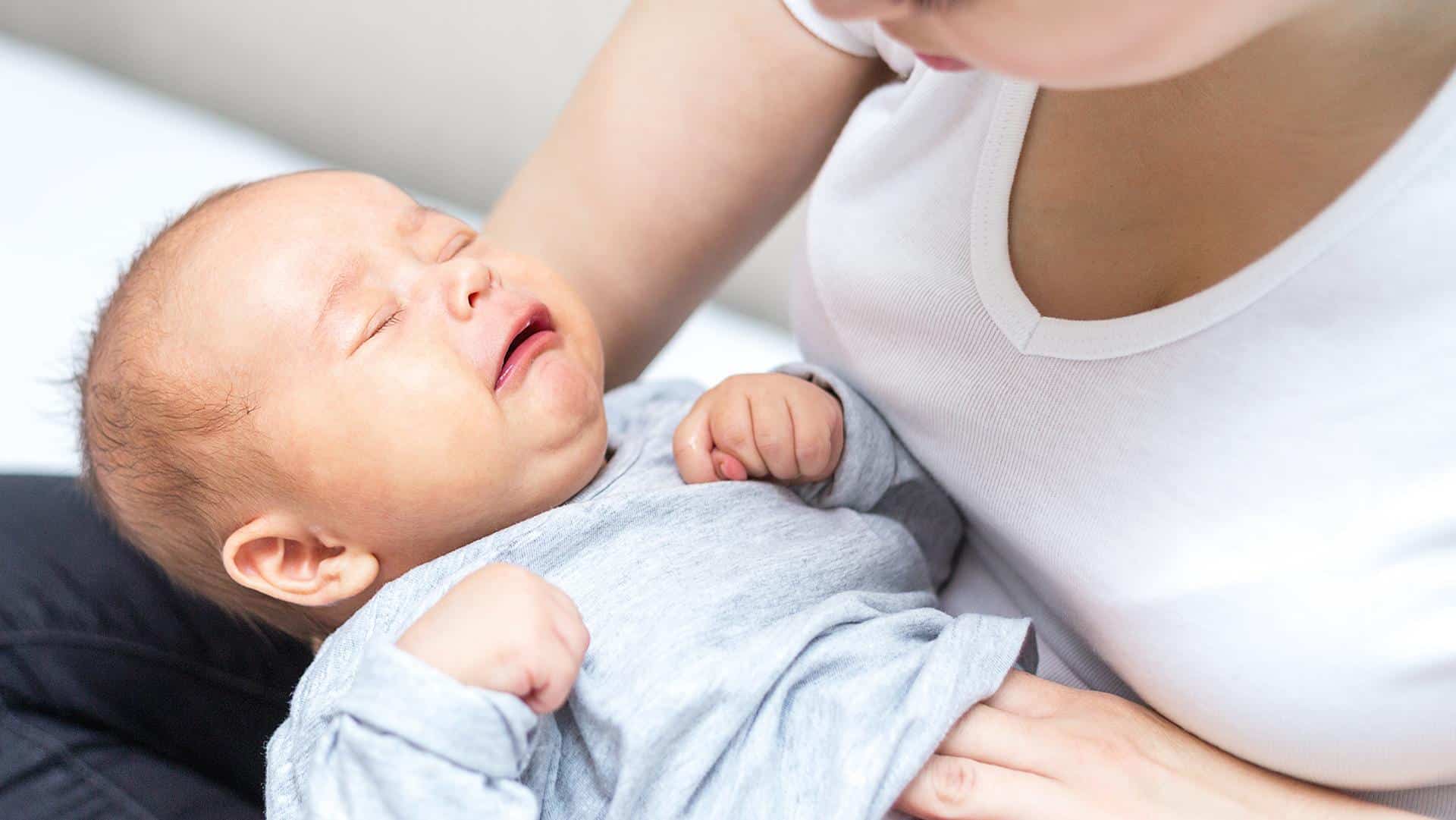 Mãe apalpando a barriga do bebê constipado